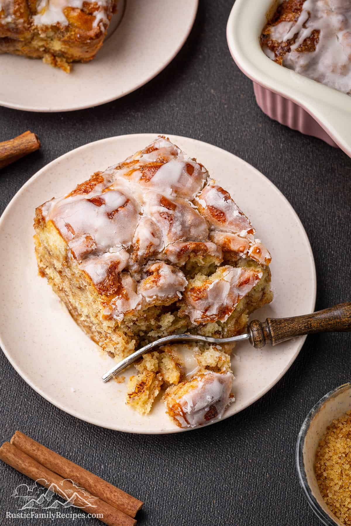 A slice of cinnamon roll casserole with a bite taken out with a fork.