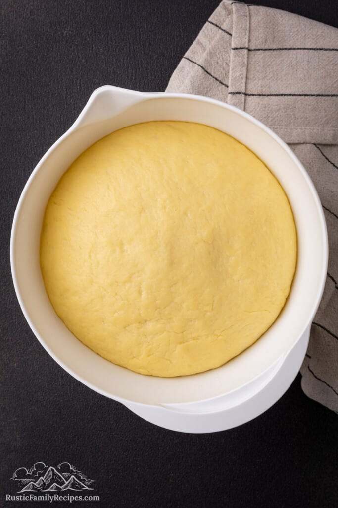 Risen dough in a white bowl.