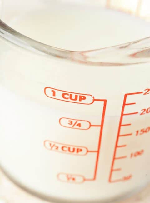 A measuring cup with milk in it an units of measurement on the side