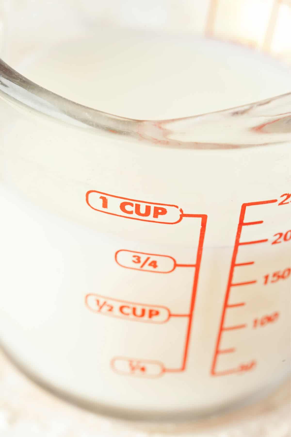 A measuring cup with milk in it an units of measurement on the side